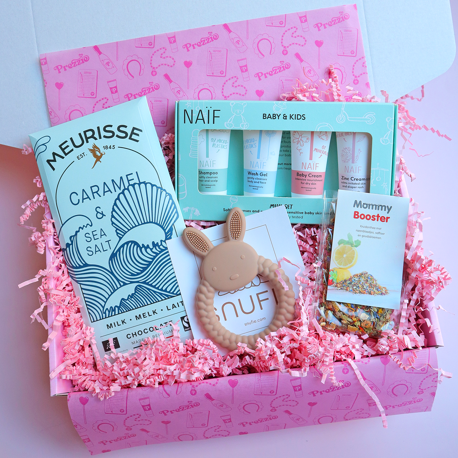 Kraamcadeaubox met Naïf verzorgingsset, bijtring, Mommy Booster thee en karamel-zeezout chocolade in roze Prezzie verpakking.