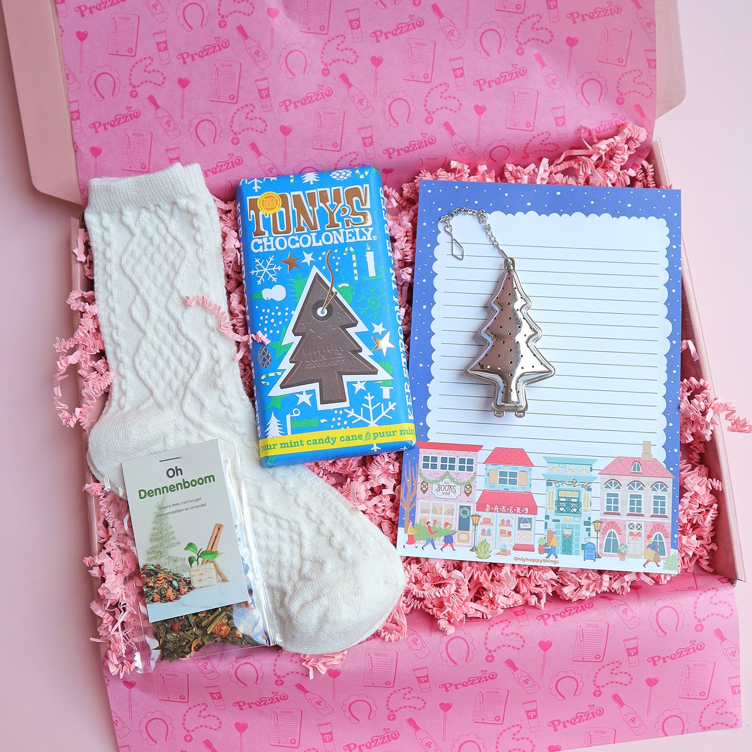 Brievenbus kerstcadeau met Oh Dennenboom thee, witte sokken, Tony’s kerstreep, kerstnotitieblok en kerstboom-theezeef in roze Prezzie verpakking.