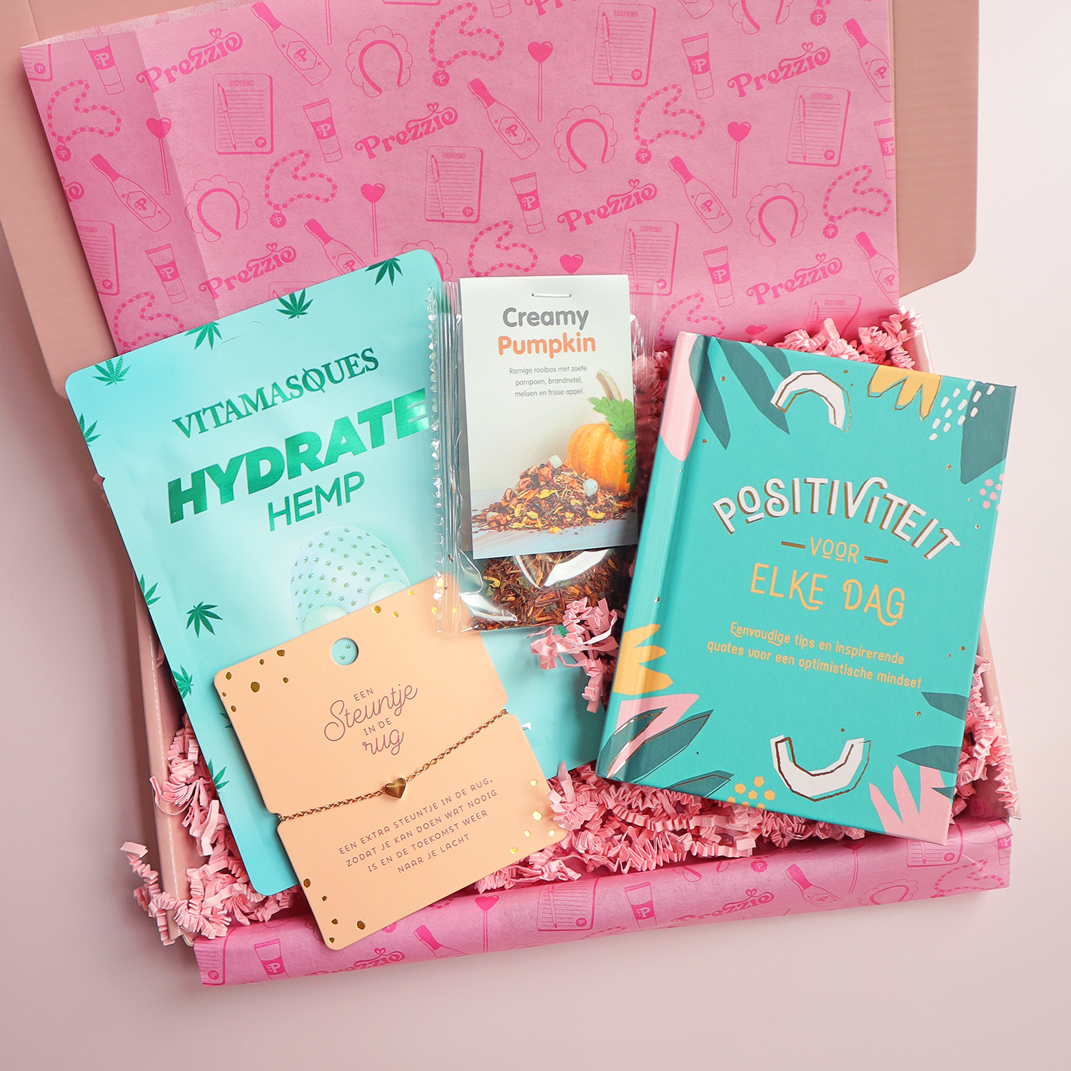 Brievenbuscadeau steuntje in de rug met gezichtsmasker, thee, boek en armband in roze cadeaudoos.