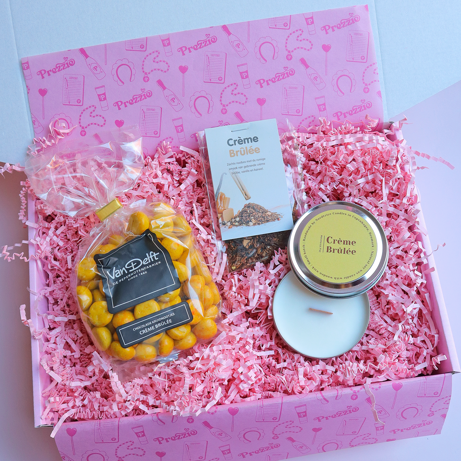 Cadeaubox met crème brûlée kaars, thee en Van Delft kruidnoten in roze Prezzie verpakking.
