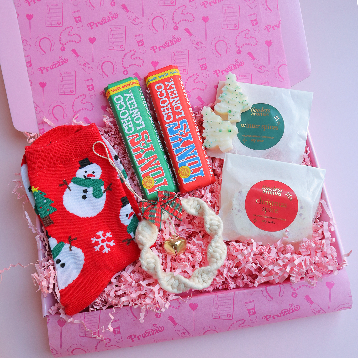 Brievenbus kerstcadeau met sneeuwpopsokken, mini Tony’s repen, kerstwaxmelts en macramé sleutelhanger in roze Prezzie verpakking.
