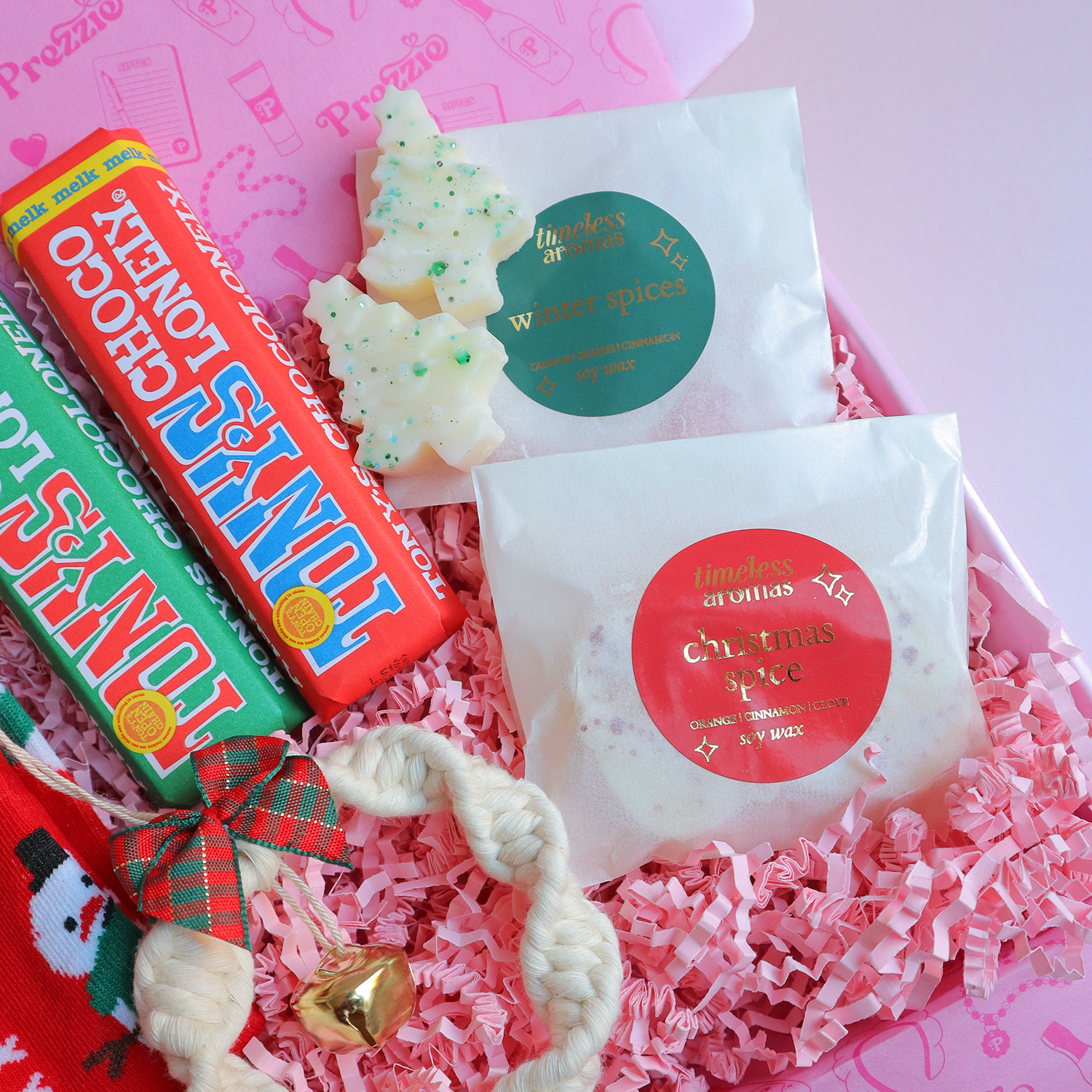 Brievenbus kerstcadeau met sneeuwpopsokken, mini Tony’s repen, kerstwaxmelts en macramé sleutelhanger in roze Prezzie verpakking.