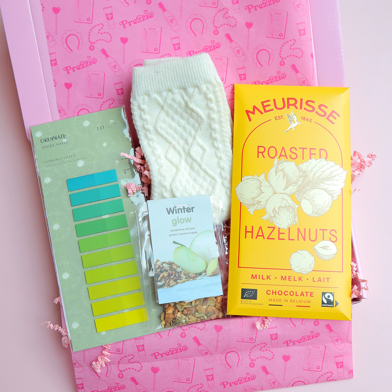 Cadeaubox met Meurisse chocolade, Winter Glow thee, witte sokken en groene sticky notes in roze Prezzie verpakking.