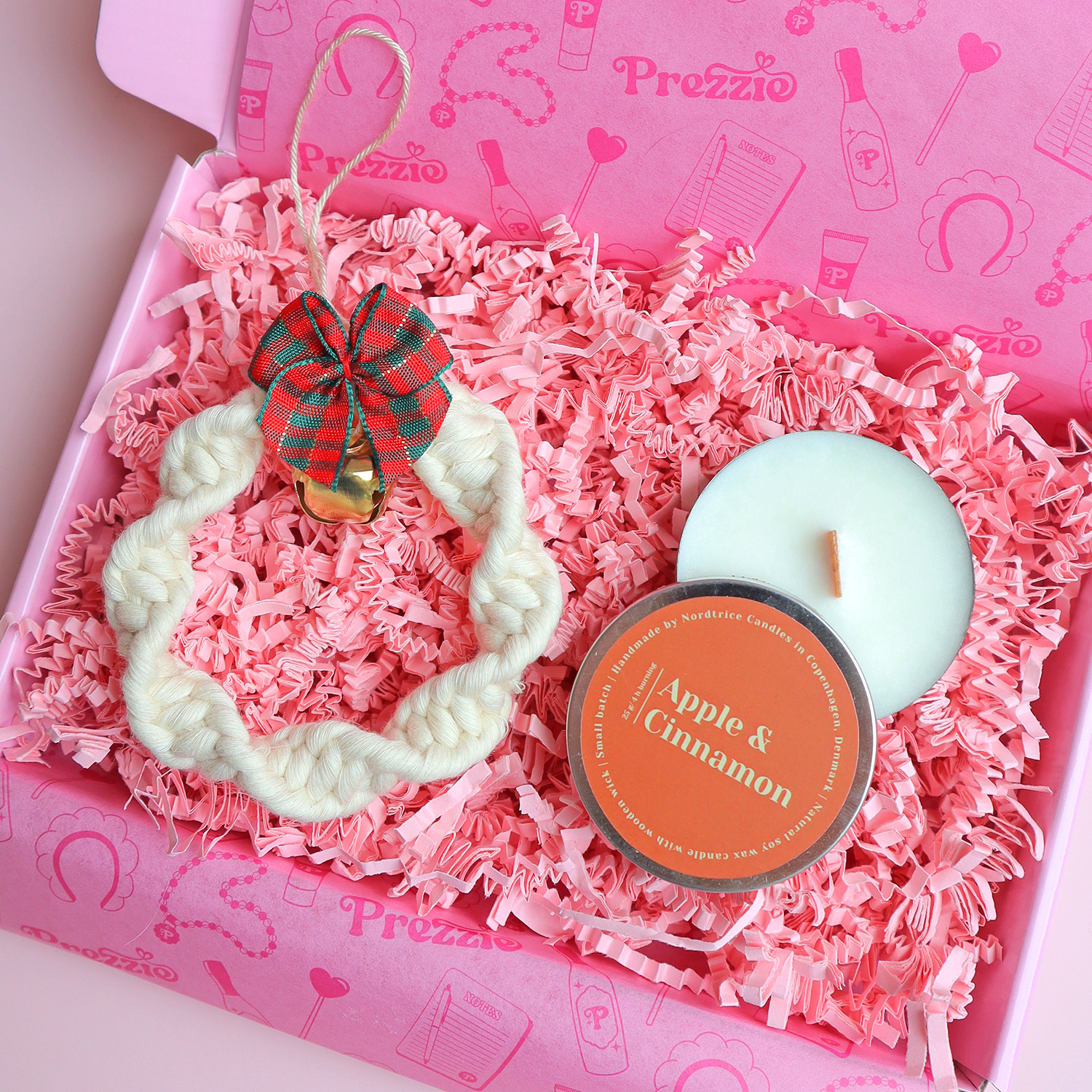 Brievenbus kerstcadeau met handgemaakt macramé kerstornament en kleine Apple & Cinnamon geurkaars in roze Prezzie verpakking.