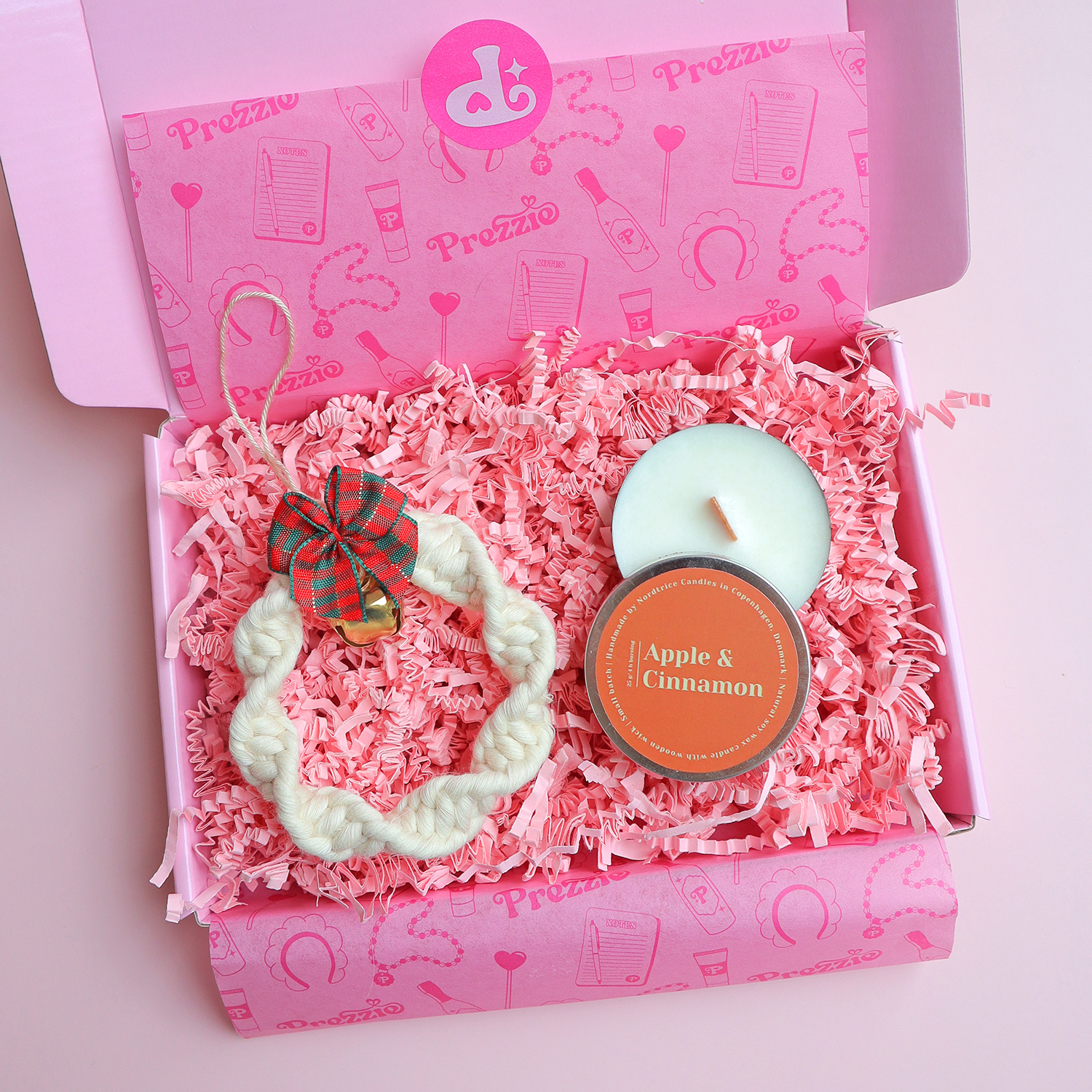 Brievenbus kerstcadeau met handgemaakt macramé kerstornament en kleine Apple & Cinnamon geurkaars in roze Prezzie verpakking.