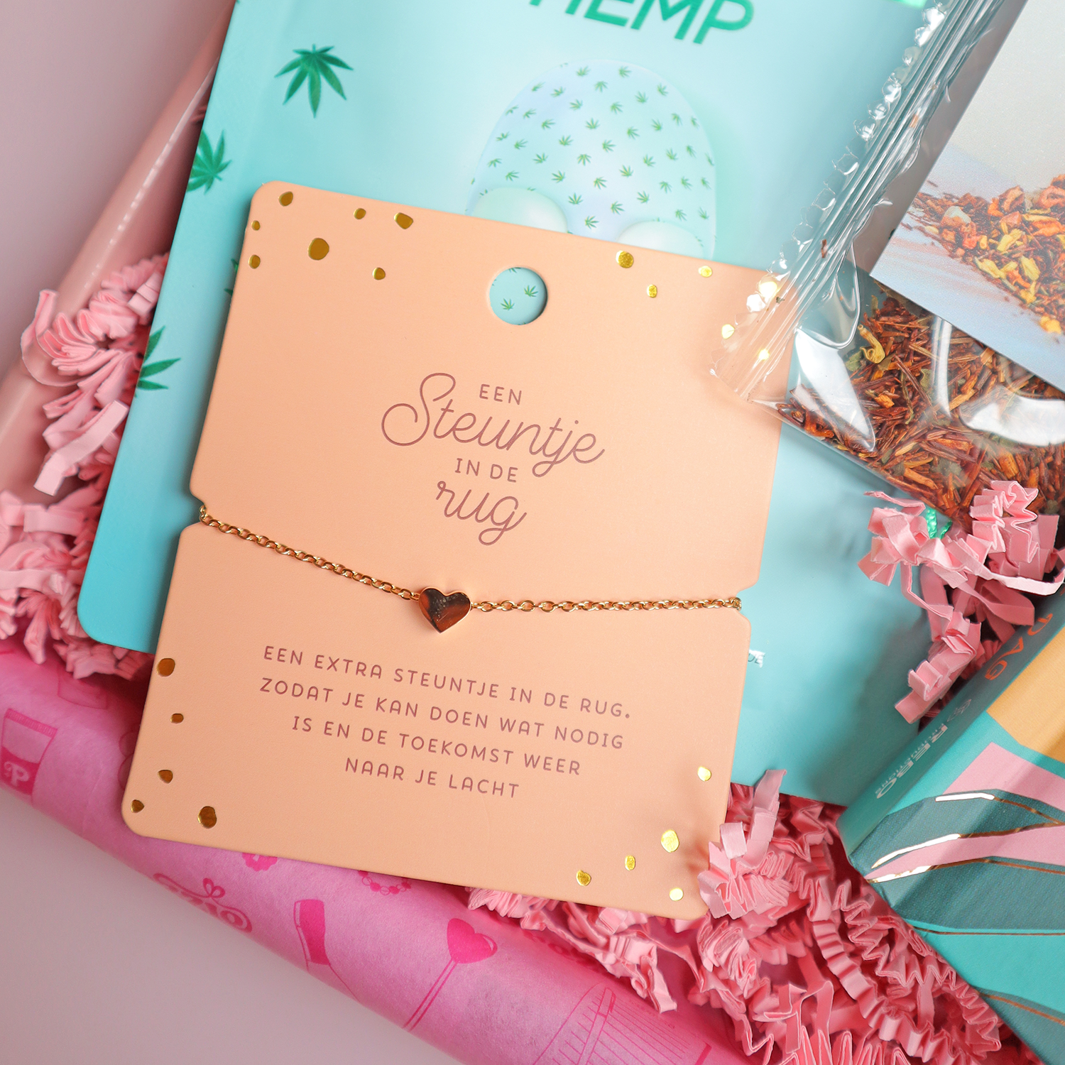 Brievenbuscadeau steuntje in de rug met gezichtsmasker, thee, boek en armband in roze cadeaudoos.